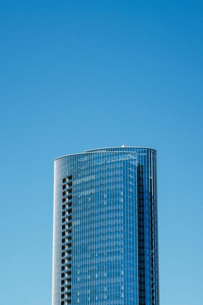 A sleek modern skyscraper rises against a cloudless blue sky, showcasing contemporary architecture.